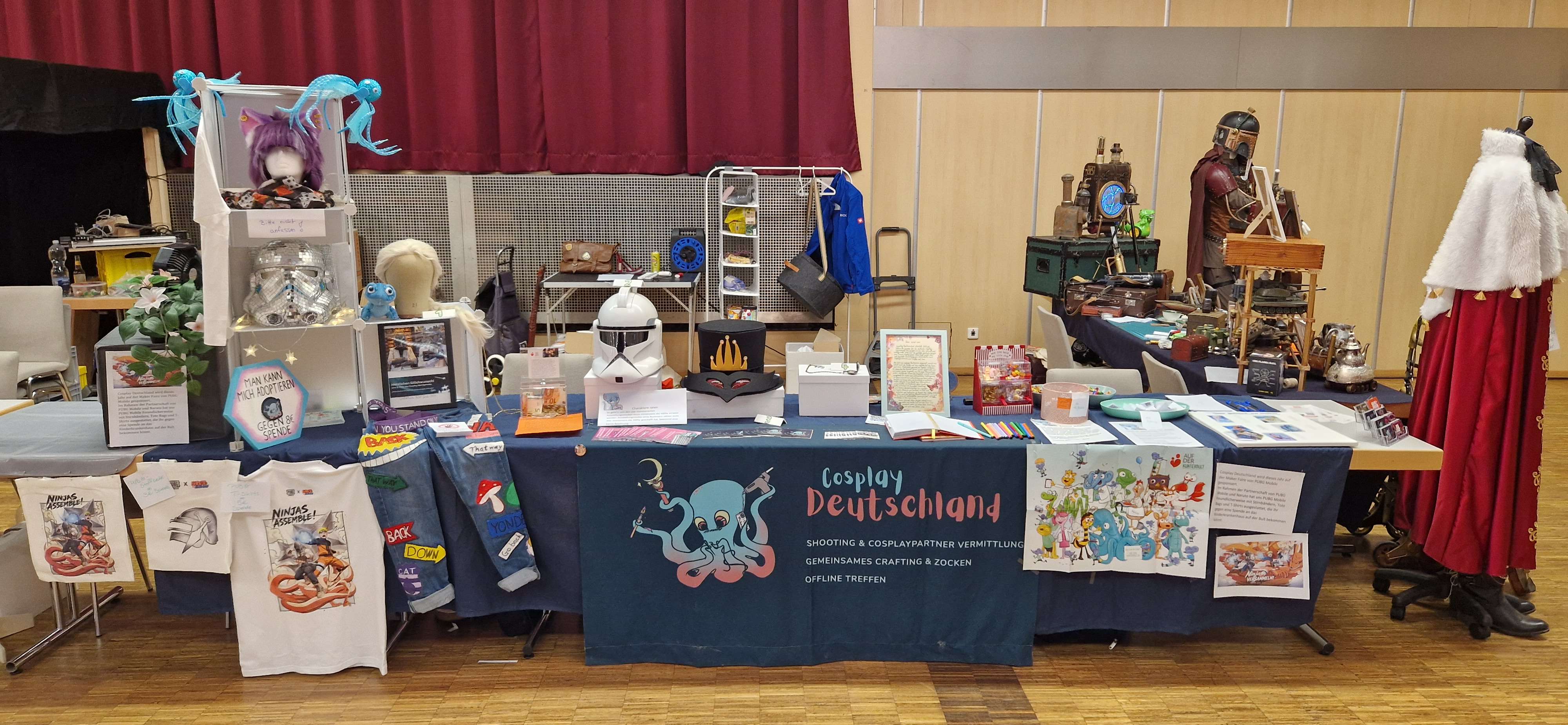 Der Ausstellungsstand von Cosplay Deutschland mit Merchandise, Kunstdrucken und einem Banner.